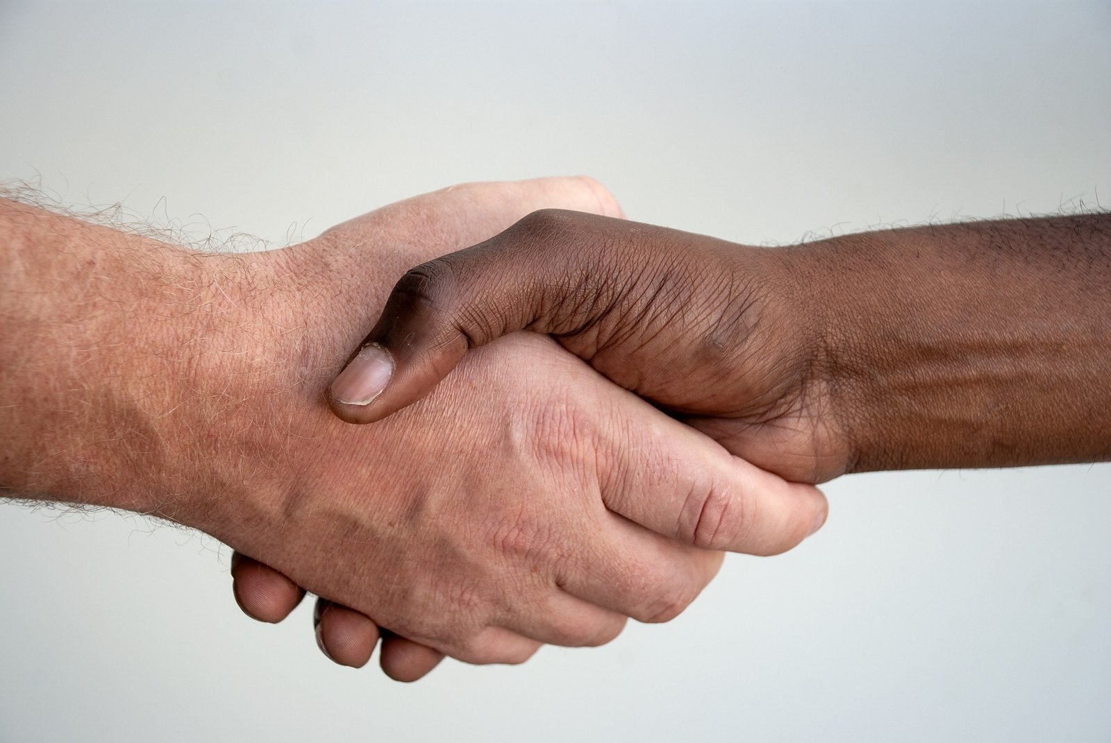 Une poignée de main entre deux personnes, mettant en avant la collaboration et le respect. L'image en noir et blanc affiche le mot "Bienveillance" écrit en blanc au centre.